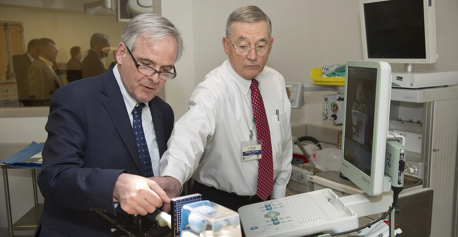 A medical physicist demonstrates brachytherapy equipment to a visitor.