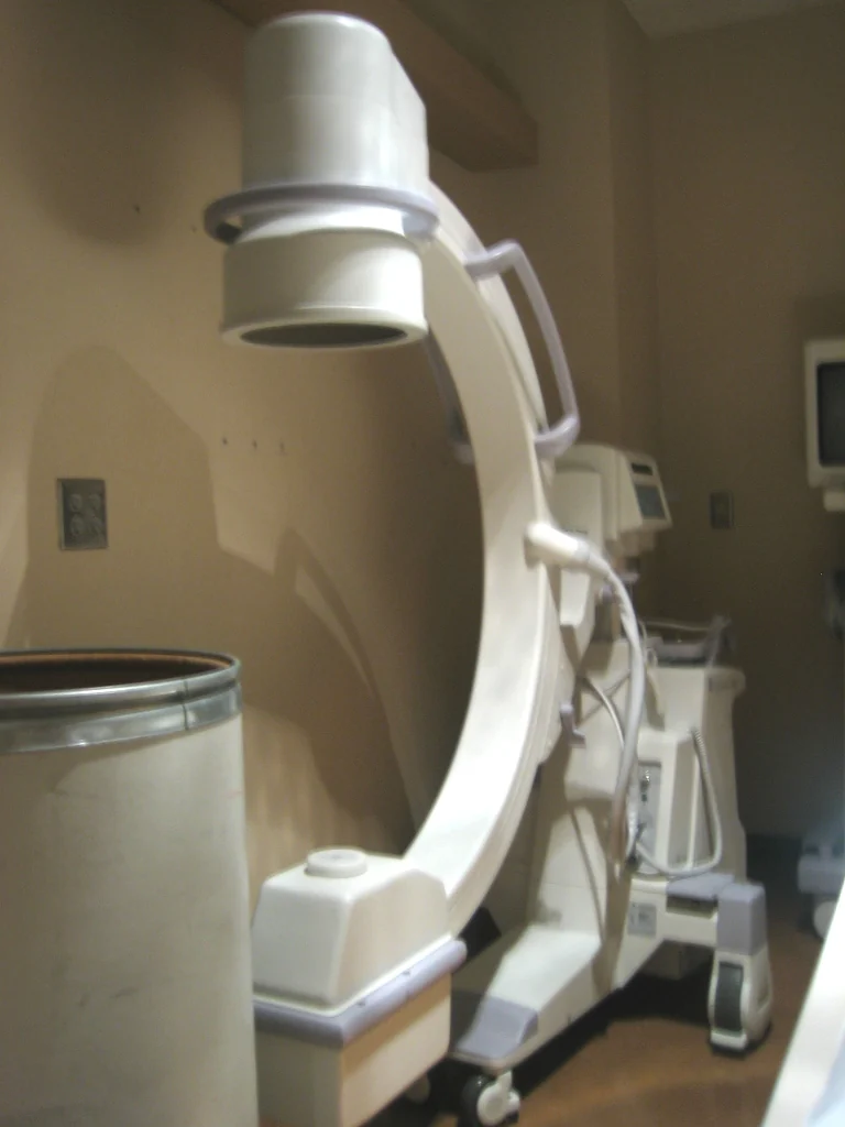 A mobile C-arm fluoroscopy unit with an attached X-ray source and detector.