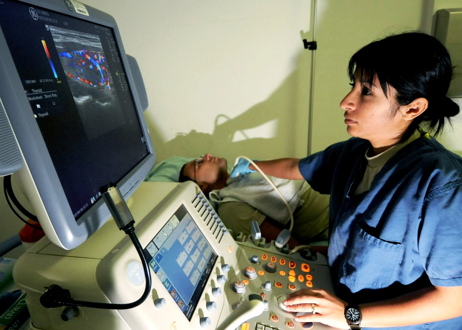 A clinician performs an ultrasound examination while viewing the scanner display.