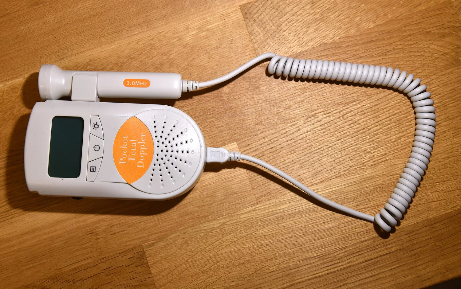 A handheld fetal Doppler ultrasound instrument with a connected probe.