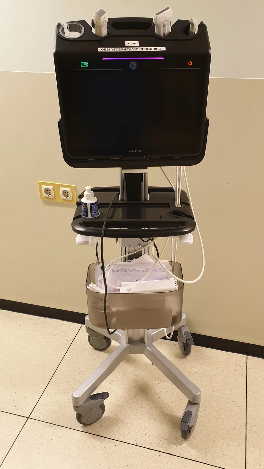A cart-mounted point-of-care ultrasound system with connected probes and gel.