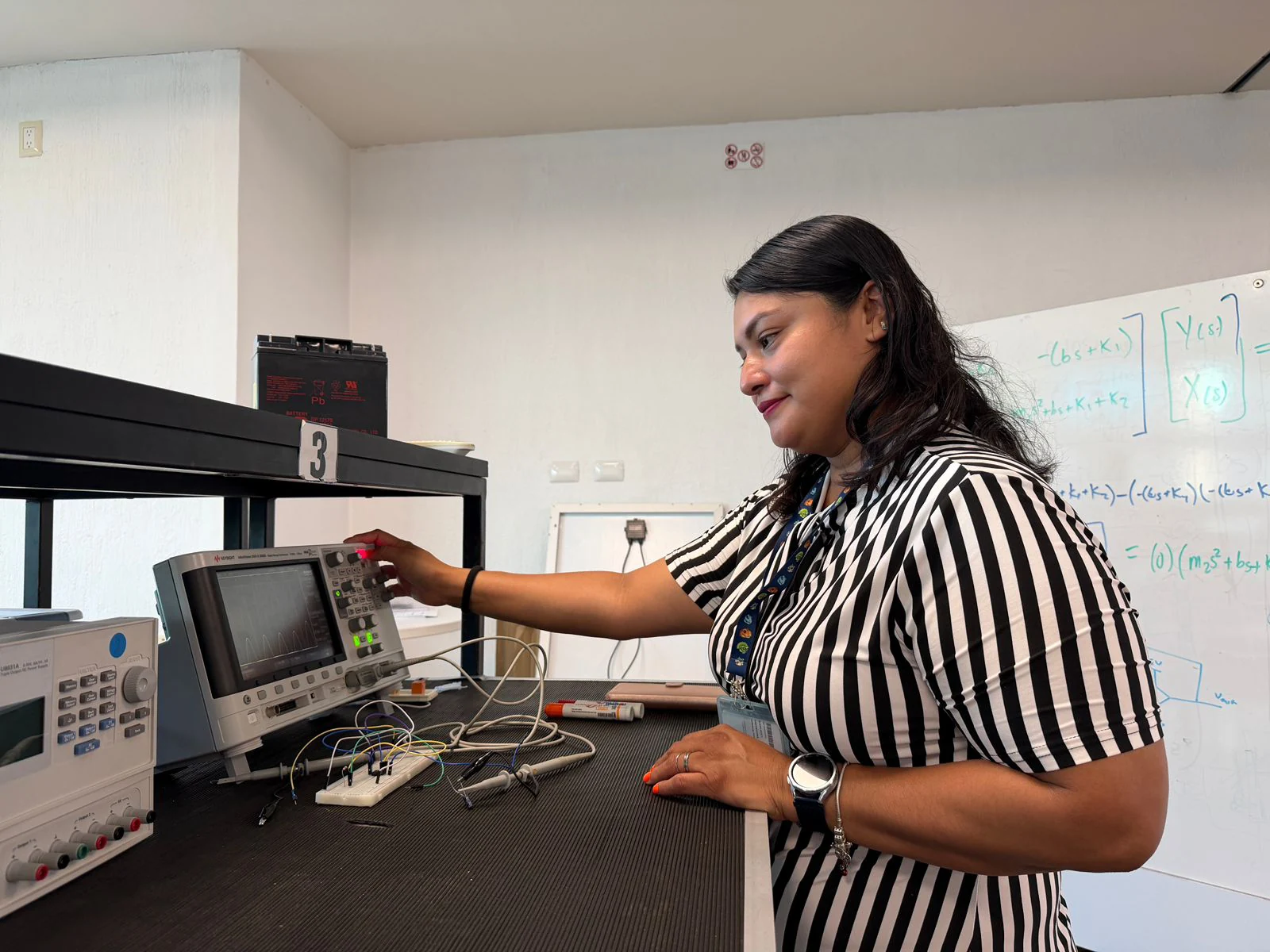 A researcher adjusts the controls of electronic measuring instruments on a laboratory bench.