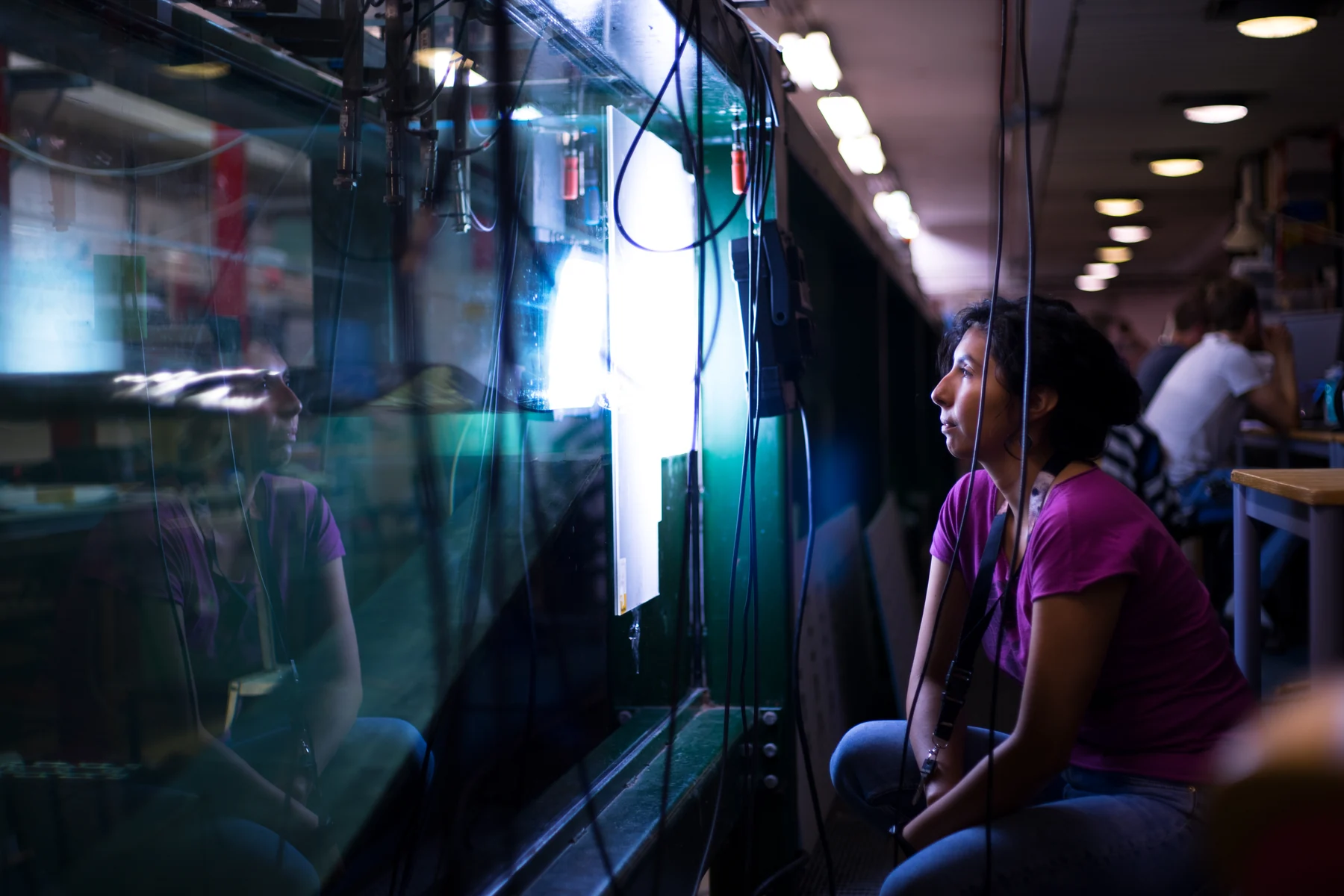 Visitors watch a bright wave demonstration through a large transparent tank.