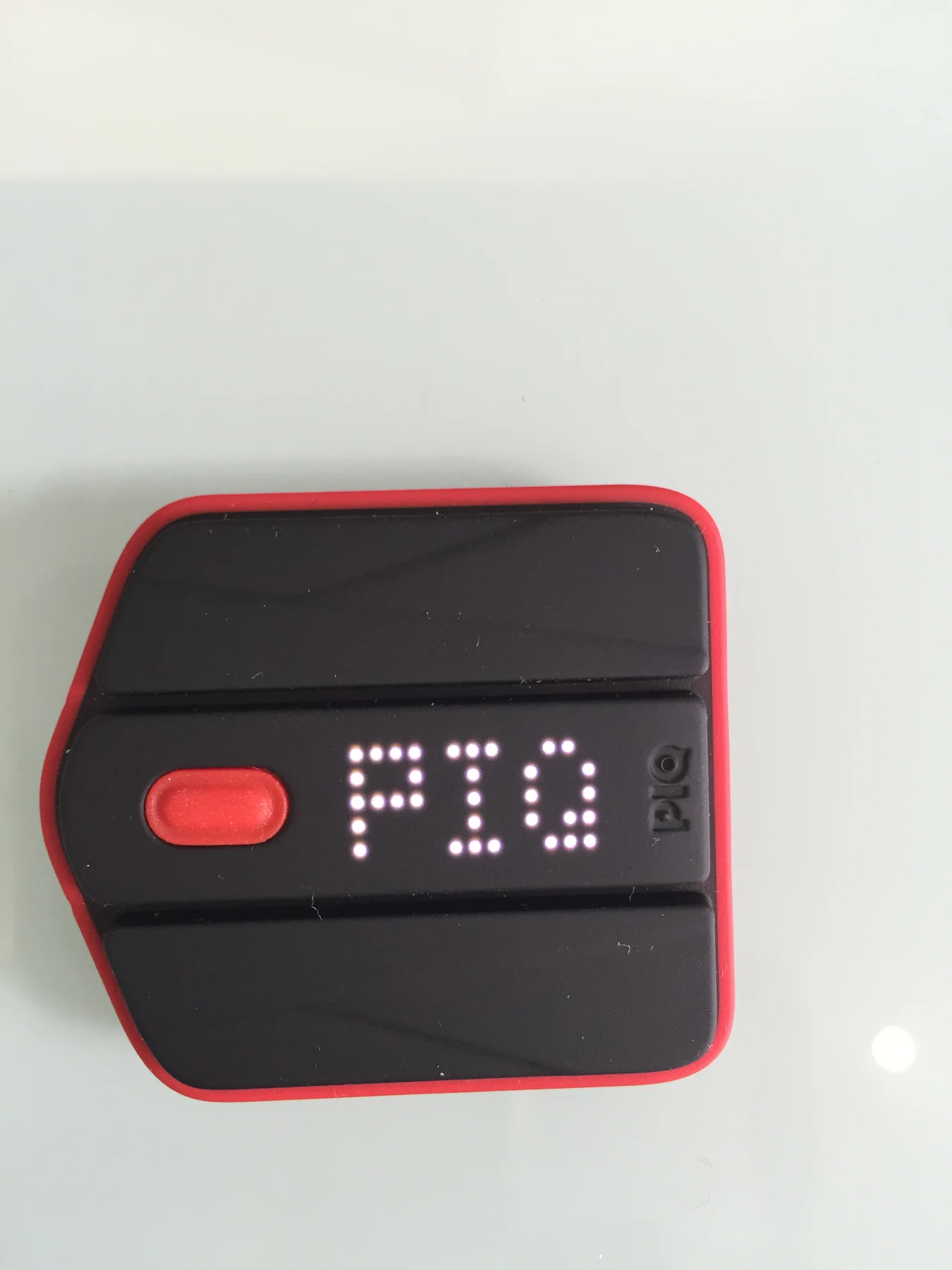 A compact black sports sensor with a red border rests on a light surface.